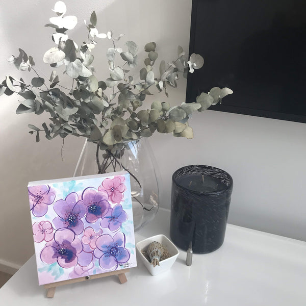 Painting of violets sitting on easel in home setting