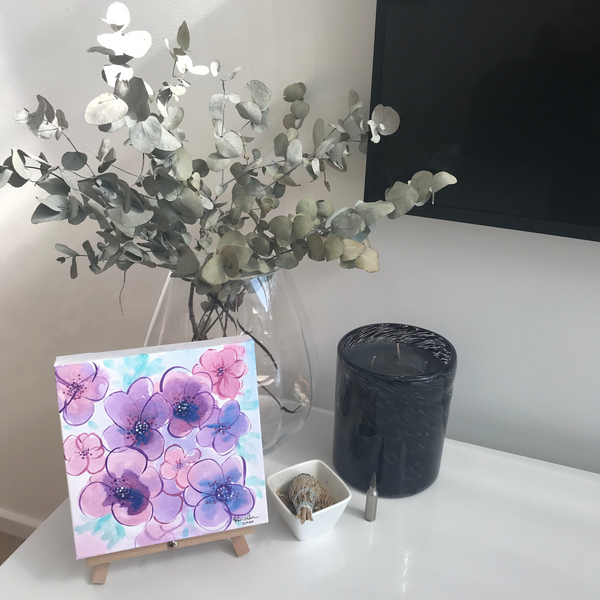 Painting of violets sitting on easel in home setting